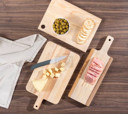 Photo for Cutting board with meat, cheese and olives on wooden table - Royalty Free Image