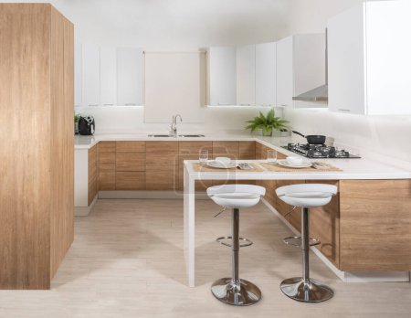 Zwei weiße Hocker stehen in einer modernen Küche mit weißen Schränken, die die Regale freilegen