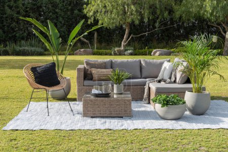 Un espacio de patio al aire libre contemporáneo con un cómodo sofá seccional, sillones, almohadas decorativas, césped verde exuberante
