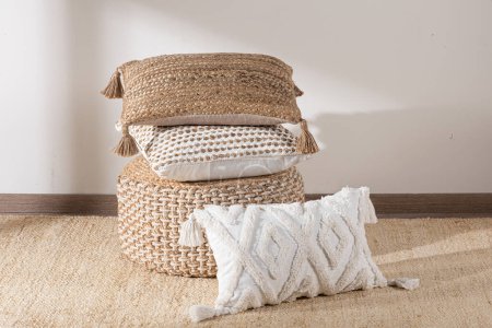 Foto de Un fondo blanco acogedor cuenta con una almohada decorativa, una cesta y una manta caliente con borlas de colores - Imagen libre de derechos