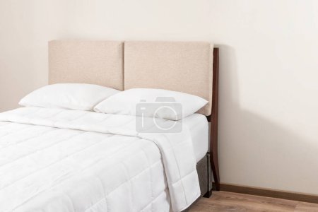 Téléchargez les photos : Cette chambre élégante dispose d'un lit moderne avec draps blancs croustillants, tête de lit contemporaine et oreillers blancs - en image libre de droit