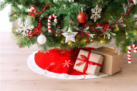 Téléchargez les photos : Arbre de Noël avec des cadeaux en dessous, jupe rouge sur un plancher de bois. Décorations de fêtes de fin d'année - en image libre de droit