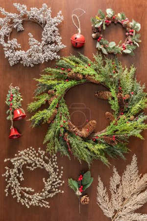 Photo for Christmas wreath set on a wooden background. The wreath is adorned with fir branches, pinecones, and berries. Top view, flat lay - Royalty Free Image
