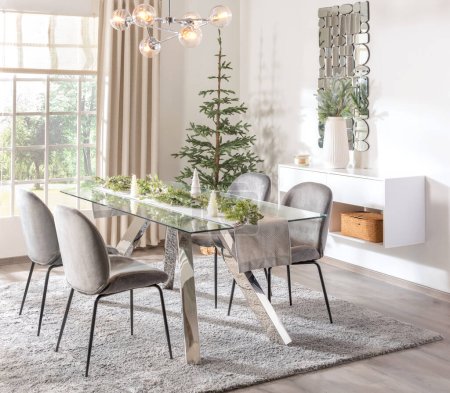 Modern white dining room interior with Christmas tree decoration and modern glass dining table furniture, beside a bright window, in Scandinavian style, side view