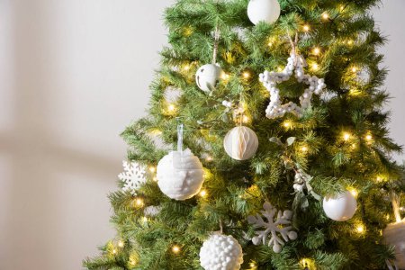Téléchargez les photos : Sapin de Noël décoré avec des ornements et des lumières boule de neige blanche, gros plan, espace de copie, intérieur de lumière naturelle - en image libre de droit