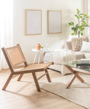 Téléchargez les photos : Intérieur d'un salon minimaliste du milieu du siècle avec une chaise longue en rotin à côté d'un canapé Chaise Longue, d'une table basse et d'un cadre d'affiche maquillé sur un mur blanc, sur un plancher en bois. - en image libre de droit