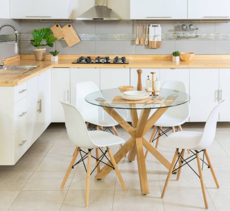 Modern Scandinavian Kitchen, Featuring a Dining Area with a Circular Glass Dining Table Set and Plastic Chairs with Wood Finish, Kitchen Cabinet with Bamboo Countertop and Cooking Accessories.