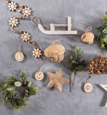 Photo for Top view of a flat lay featuring an assortment of Christmas ornaments and decorations, wooden snowflakes, decorative acorns, wooden sled, Christmas wreath and festive engravings, gray backdrop. - Royalty Free Image