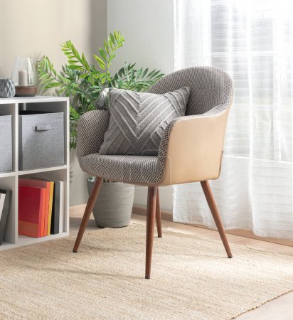 Chic Mid-Century Modern Armchair with Textured Herringbone Upholstery and Leather Accents, Wooden Legs with a Chevron Throw Pillow, in a Brightly Lit Room, Sheer Curtains and Organized Cube Shelving.