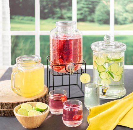 Summertime Refreshments: Crisp Lemonade and Berry-Infused Water Elegantly Displayed in Clear Glass Dispensers on a Rustic Wooden Table, Complemented by Bright Yellow Napkins and Lush Greenery Backdrop