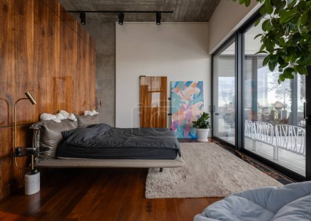 Foto de Un dormitorio con una amplia cama de madera y puertas correderas de vidrio para la luz natural y la comodidad en la casa - Imagen libre de derechos