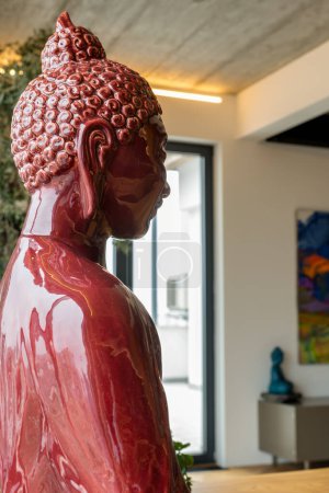 Foto de Estatuilla de Buda rojo en el fondo de una gran ventana en una habitación con paredes blancas. Foto de alta calidad - Imagen libre de derechos