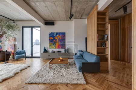 Foto de Una acogedora sala de estar con pisos de madera, un cómodo sofá, mesa, sillas y una hermosa pintura en la pared como accesorio de arte focal - Imagen libre de derechos