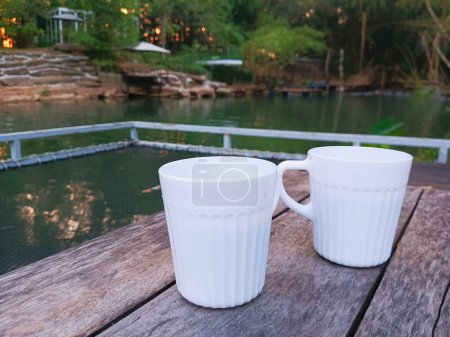 Téléchargez les photos : Deux tasses à café blanches sur une table en bois dans le jardin. - en image libre de droit
