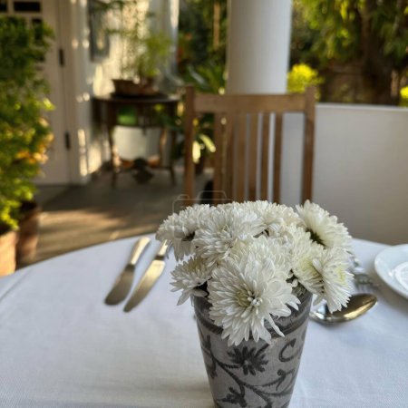 Beau bouquet de fleurs blanches dans un vase sur la table à manger.
