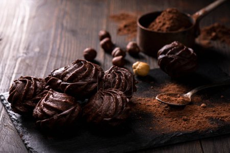 Foto de En primer plano, en un ambiente oscuro, besos de chocolate con avellanas y cacao en polvo. - Imagen libre de derechos