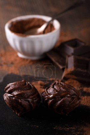 Téléchargez les photos : Au premier plan, dans un environnement sombre, bisous au chocolat, poudre de cacao et morceaux de chocolat noir. - en image libre de droit