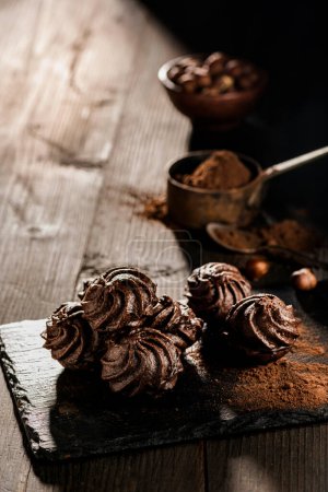 Foto de En primer plano, en un ambiente oscuro, besos de chocolate con avellanas y cacao en polvo. - Imagen libre de derechos