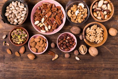 Foto de Top view, on an old wooden background, a large assortment of dried fruits placed in various bowls and on the table. - Imagen libre de derechos