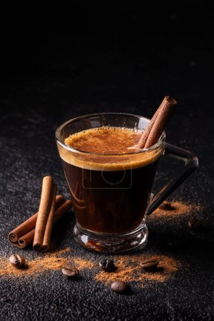Photo for In the foreground, espresso coffee in a glass cup flavored with ground cinnamon - Royalty Free Image