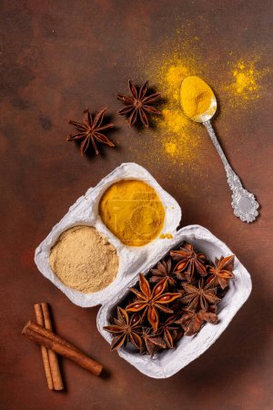 Photo for On a rustic background, in a container of eggs, turmeric, ginger powder and star anise. - Royalty Free Image