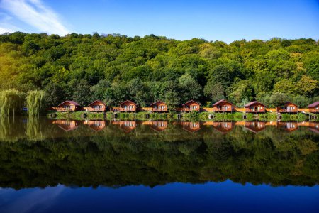 Photo for Wooden houses on the water near the forest for carp fishing. A place to relax in nature. Spring carp fishing season. - Royalty Free Image