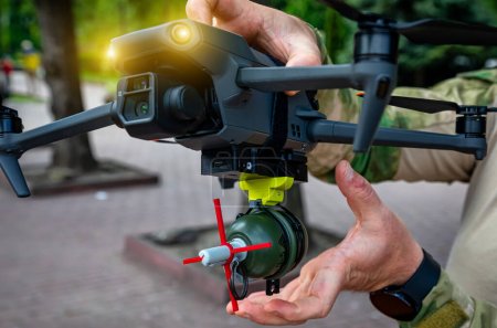 Un soldat attache une grenade explosant un ennemi avec un drone militaire. Concept utilisant des quadrocoptères dans la guerre intelligente en Ukraine.