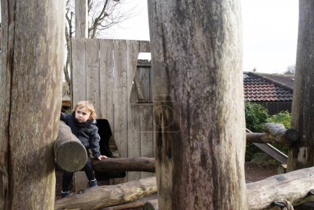 Child at the playground, climbing wooden logs.