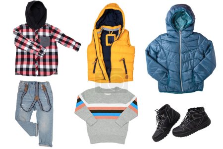 Collage of children clothes. Set of a stylish hooded down vest, a rain jacket, a trendy hoddie shirt, denim jeans, a sweater and boots for boy. Spring autumn and winter fashion. Isolated.