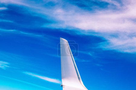 View of the part of a wing of an aeroplane or airliner in flight out of the window with blue sky and light clouds. Wing of aircraft. Copy space.