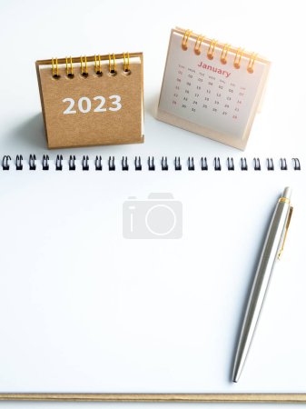 2023 to do list concept. White blank space on spiral notepad, horizontal style with pen and 2023 year desk calendar cover with January page on white background. Goals and target in new year.