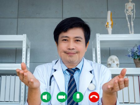 Photo for Asian man orthopedic doctor looking at camera on webcam screen with video call icons, online video conference with patient, and remote medical chat consultation. Telemedicine with physician concept. - Royalty Free Image