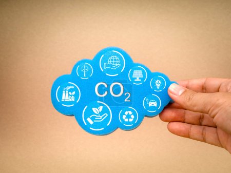 Reduce CO2 emissions, limit climate change, net zero carbon dioxide footprint reduction concepts. Reduce CO2 icon and renewable energy symbol on cloud sponge hold by hand on recycle paper background.