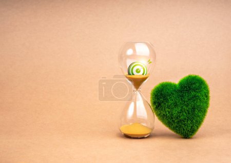 Environment sustainability, time and responsibility concept. Target of restoring our earth. 3d green target icon in hourglass and green grass heart shaped on recycle paper background with cop space.