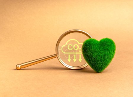 Environmental sustainability, Net zero carbon dioxide reduction concept. Co2 emission reduction icon in magnifying glass lens near green grass heart ball on recycle paper background with copy space.
