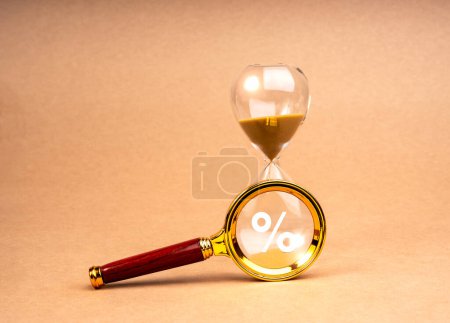 Tax time deadline concept. Percentage icon in magnifying glass lens on hourglass, isolated on brown recycled paper background, minimal style. Interest Rate Swap (IRS), Time limit for annual taxation.