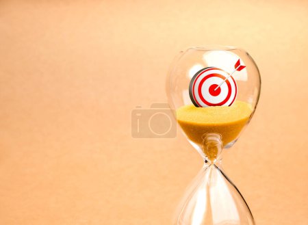 Photo for Short-term business goals encompass work that helps an organization reach its mid-term goals concept. Close-up 3d target icon in hourglass on brown recycle paper background. Successful is coming soon. - Royalty Free Image