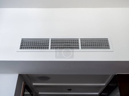 Front view of air conditioning wall mounted ventilation system on ceiling in the black and white hotel room. Hotel room air ventilation grill on the wall.