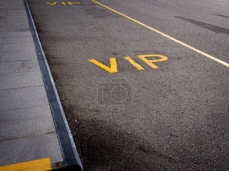 VIP-Parkstreifen-Service-Konzept, Text auf dem leeren schwarzen Asphaltstraßenhintergrund. Dunkle Straße mit langer gelber Schlange mit VIP-Haltestelle in der Nähe des Fußweges am Hotel oder Flughafen.
