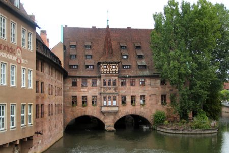 Photo for Nuremberg, Germany - August 25, 2023: Ancient Nurnberg Heilig Geist Spital building, or Hospital of the Holy Ghost on Pegnitz river. - Royalty Free Image