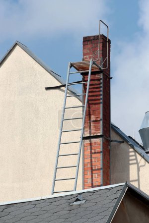 Old brick smokestack on a rooftop with a metal ladder for servicing