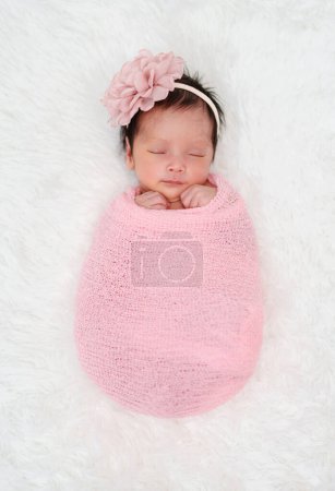 Téléchargez les photos : Happy newborn baby girl sleeping in cloth wrap blanket on a bed - en image libre de droit