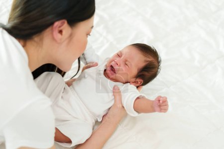 Photo for Newborn baby crying while mother holding on a bed - Royalty Free Image