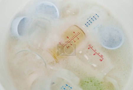 Photo for Bottle of milk are washing in plastic basin - Royalty Free Image