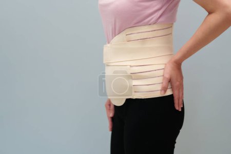 Photo for Woman wearing lumbar support belts. pregnant and postnatal lumbar brace after surgery - Royalty Free Image