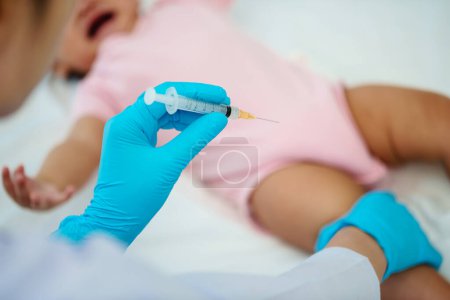Téléchargez les photos : Médecin tenant la seringue et préparant le vaccin injectant à la jambe du bébé bab pleurer - en image libre de droit