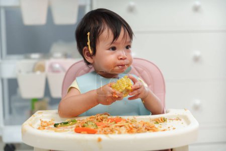 Téléchargez les photos : Bébé bébé manger des aliments et légumes en se nourrissant BLW ou bébé conduit sevrage sur une chaise - en image libre de droit