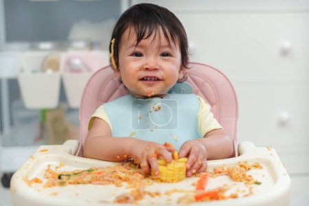 Téléchargez les photos : Heureux bébé bébé manger des aliments et légumes en se nourrissant BLW ou bébé conduit sevrage sur une chaise - en image libre de droit