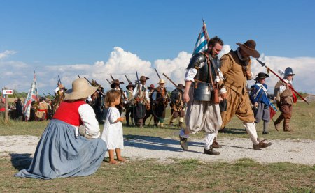Photo for PALMANOVA, Italy - September 4, 2022: A woman and a small girl watching reenactors parading after the battle during the Seventeenth Century annual historical reenactment - Royalty Free Image