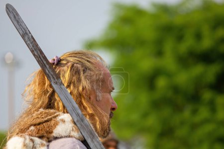Foto de AQUILEIA, Italia - 22 de junio de 2014 - Primer plano de un hombre caucásico rubio de pelo largo visto de perfil interpretando el papel de un antiguo guerrero celta en la recreación histórica romana anual - Imagen libre de derechos